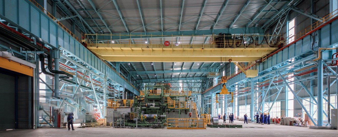 Industrial steel mill interior, factory workers monitoring production