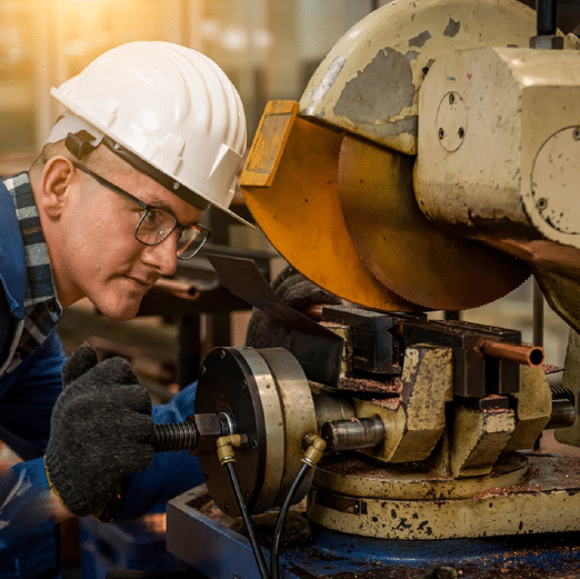 Worker examining a machine in a precision manufacturing setup.