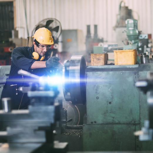 Worker using advanced machining tools in factory settings.