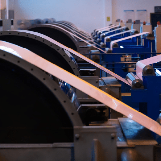 Steel coils being carefully processed and packaged in an industrial facility.