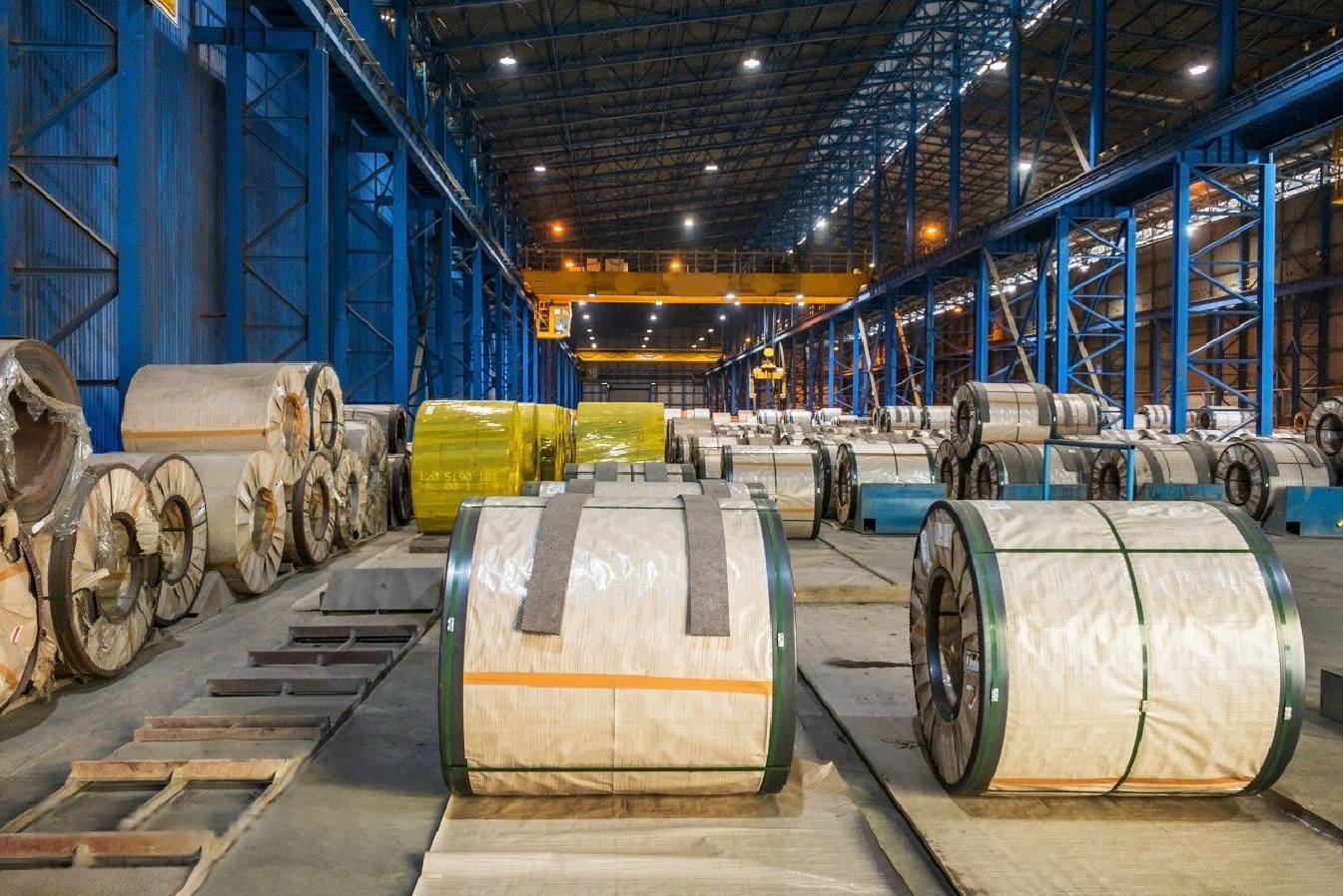 Wrapped stainless steel coils stored in a large warehouse, showing MFY’s organized export logistics