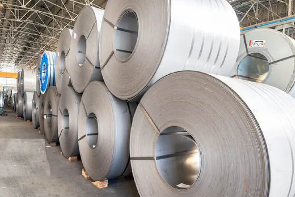 Stack of high-quality stainless steel coils in a warehouse, ready for export and manufacturing use.