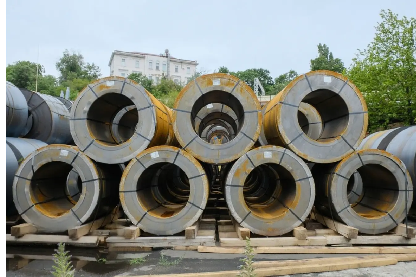 Stacked industrial stainless steel coils ready for shipping in outdoor warehouse