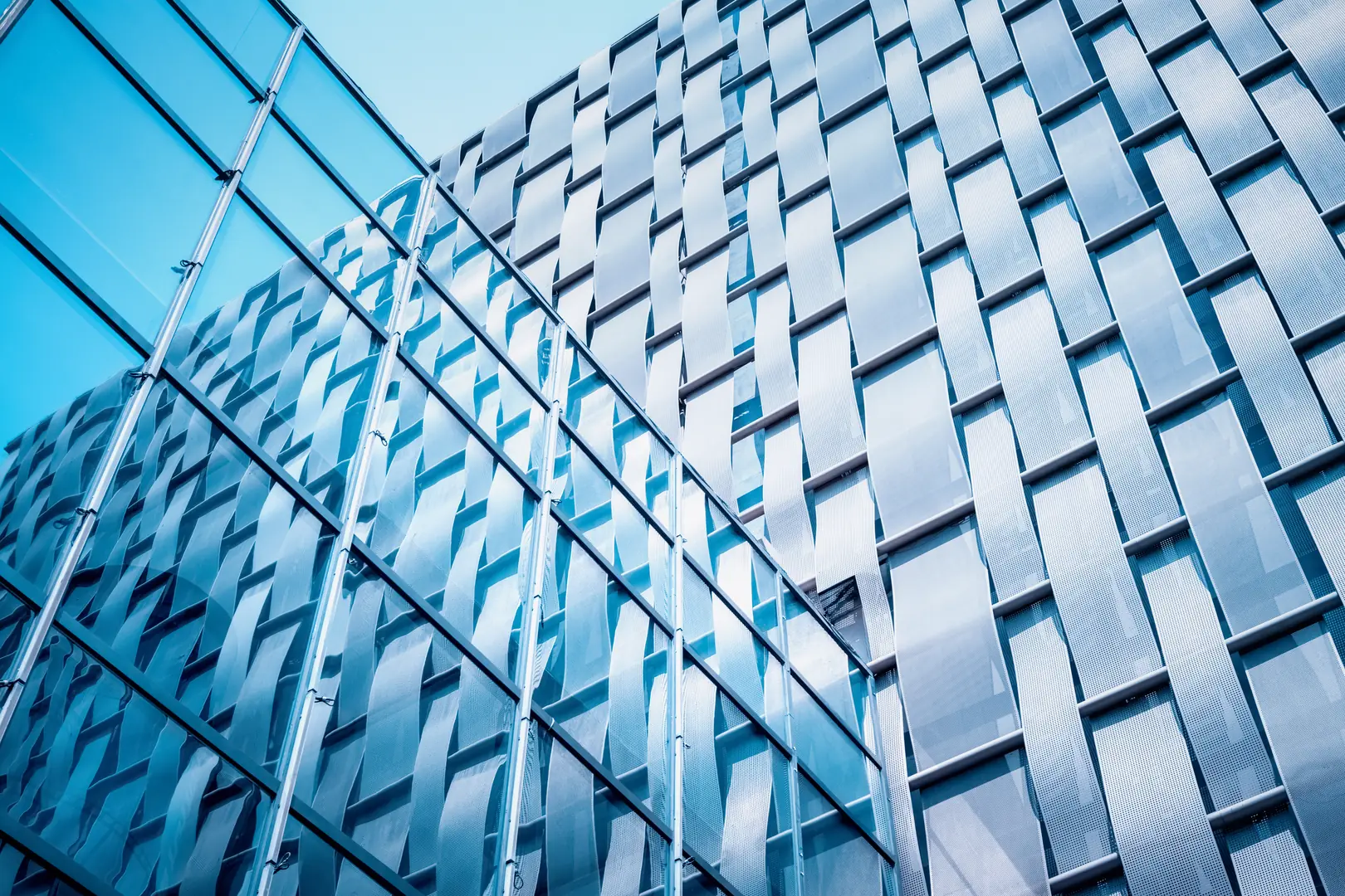 Close-up view of contemporary building facade with stainless steel panels reflecting blue sky