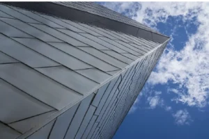 Close-up of a modern building facade with stainless steel panels against a bright blue sky