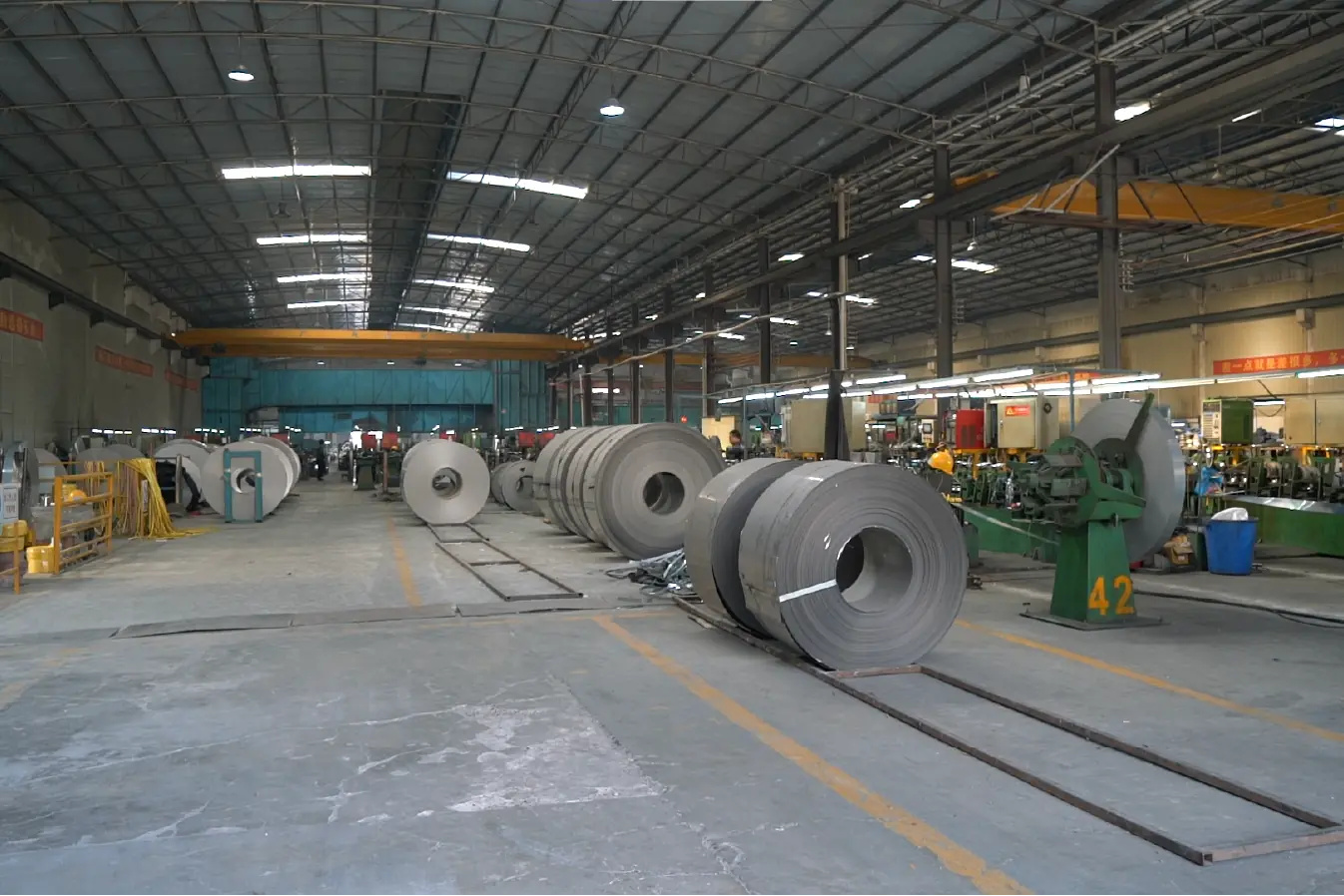 Interior view of MFY's stainless steel factory with large steel coils and processing equipment