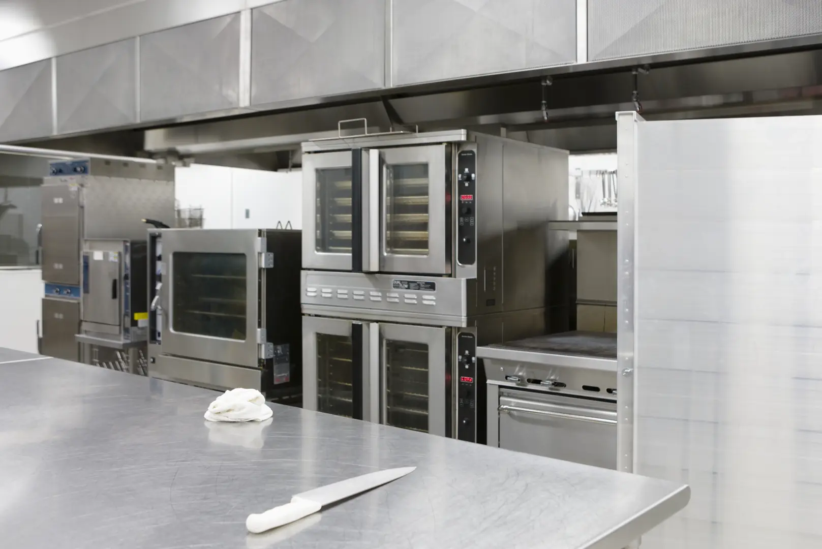 Professional kitchen with stainless steel appliances and countertop featuring ovens and cooking equipment