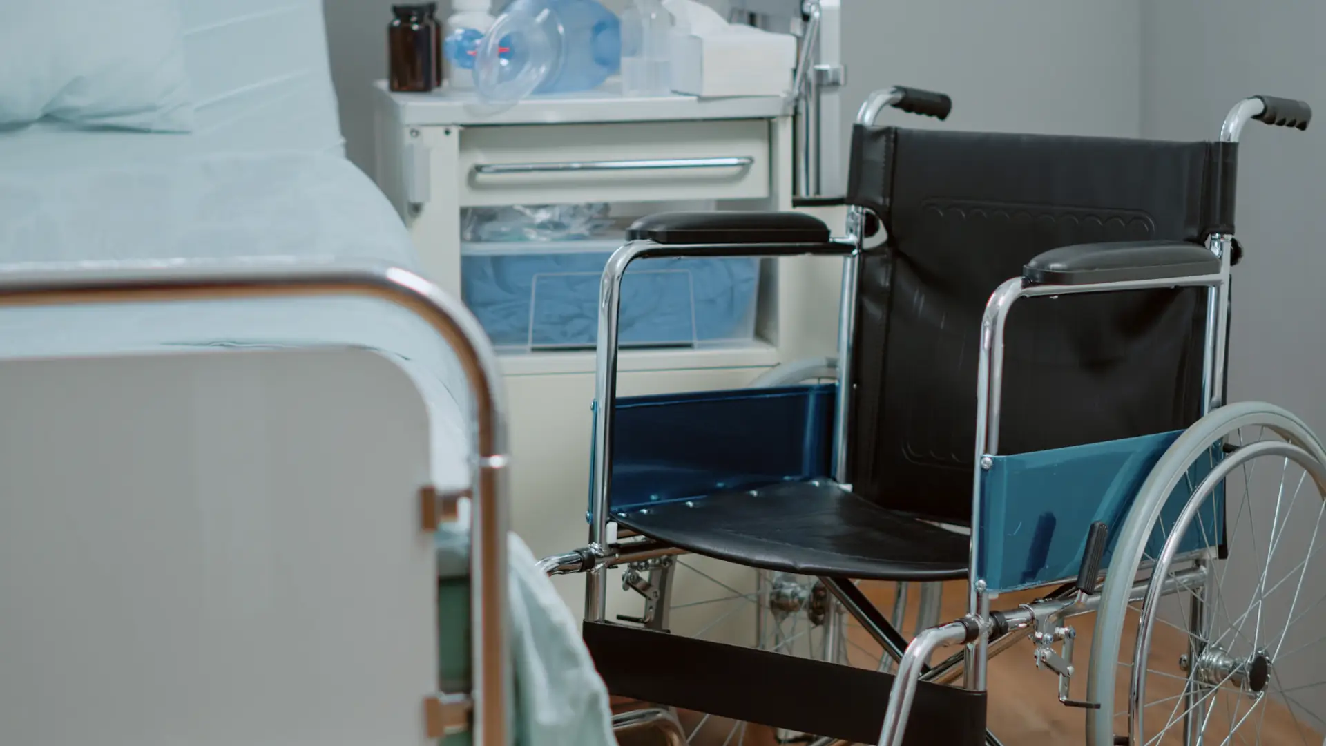 Empty wheelchair next to hospital bed in medical facility